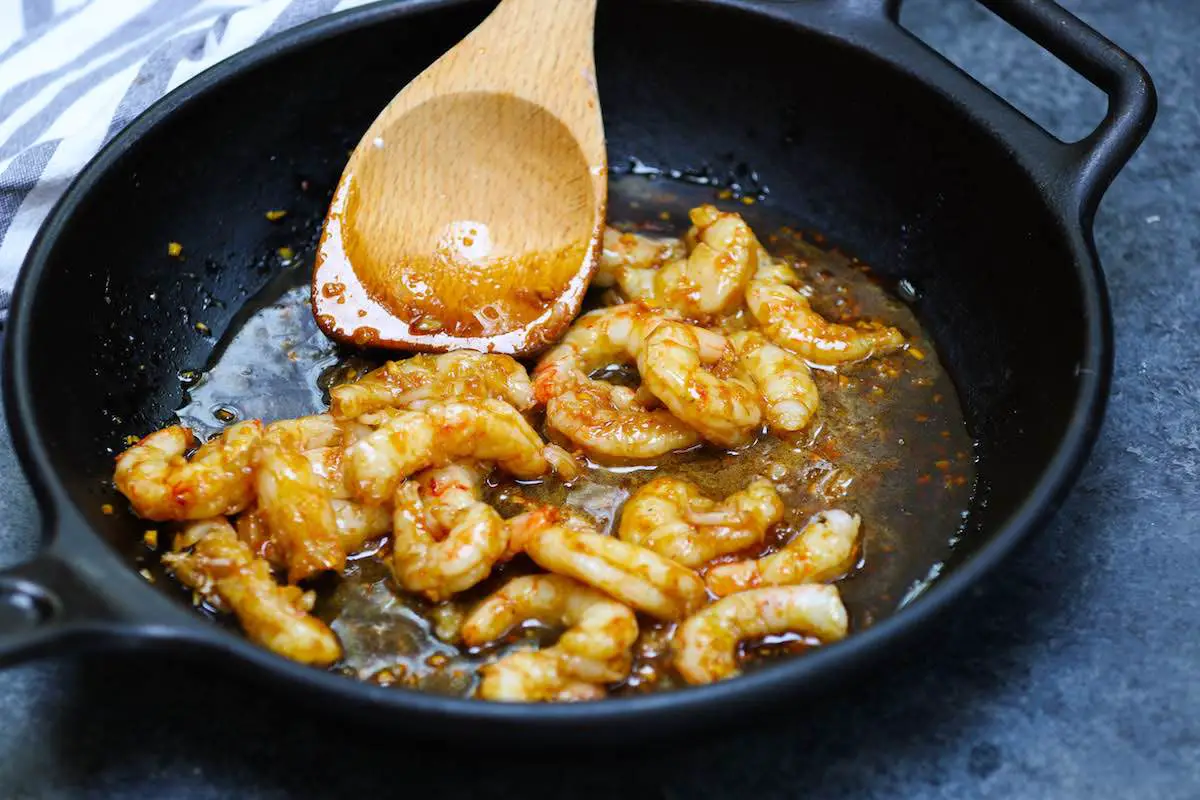 Mélanger les crevettes cuites avec du miel et de la sauce à l'ail.