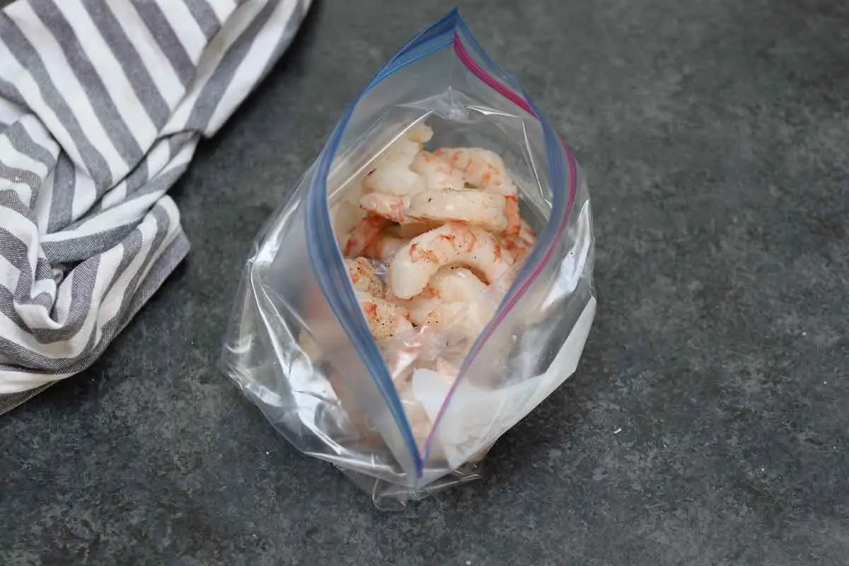 Ajouter les crevettes, l'huile, le sel et le poivre dans un sac hermétique.