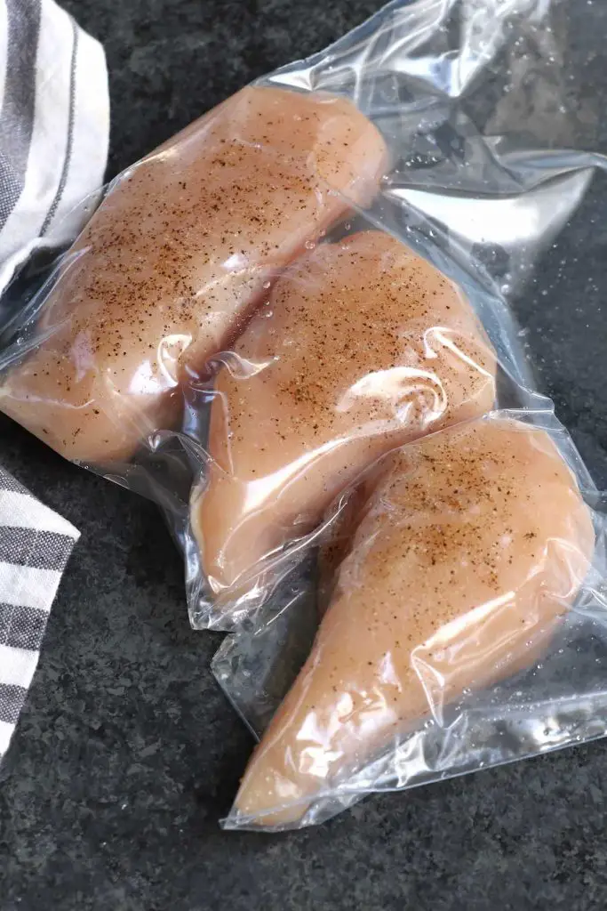 Poitrines de poulet assaisonnées, emballées sous vide dans un sac à fermeture éclair.