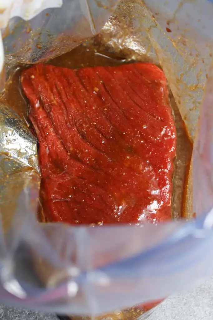 Faites mariner un steak de haut de ronde dans un sac à fermeture éclair.