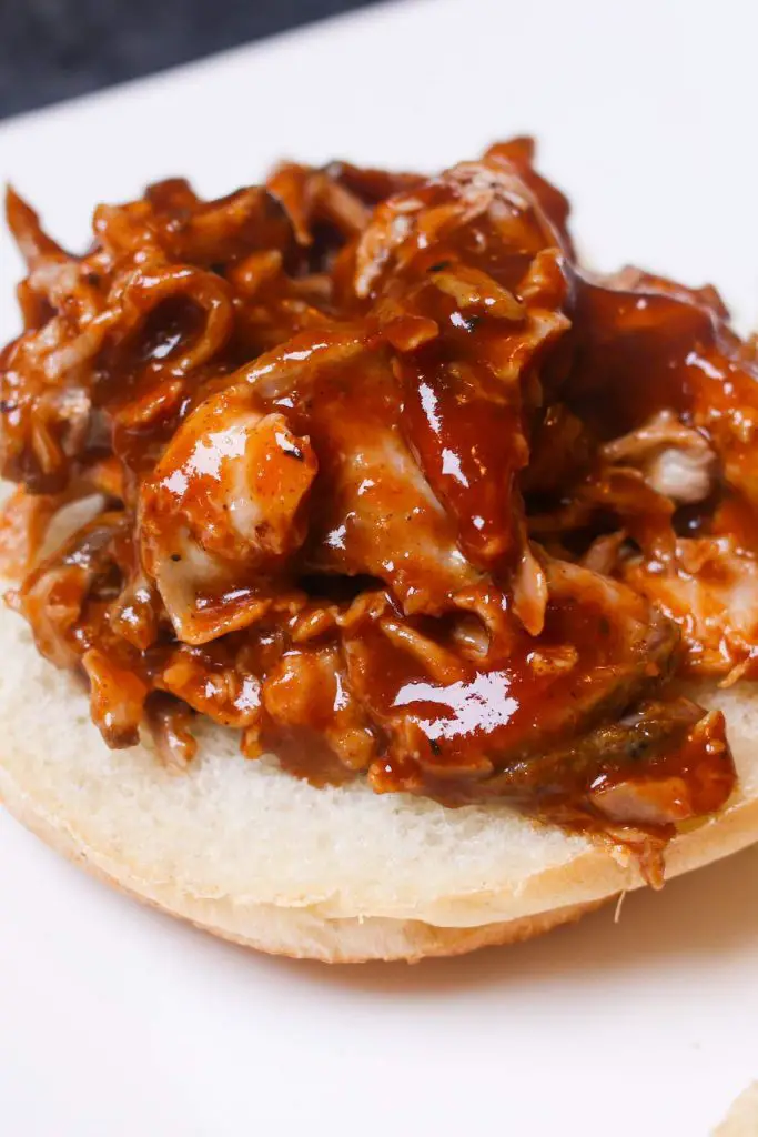 Ajouter la sauce BBQ au porc effiloché sur un petit pain hamburger.